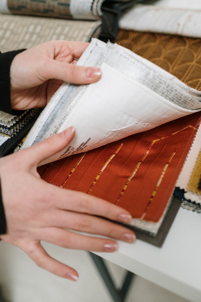 Close-up of hands examining various textured fabric swatches in a book.
